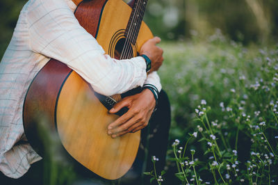 Midsection of man holding guitar in park