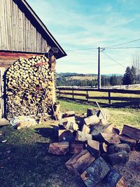 Stack of logs on field against sky