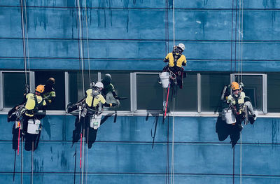 Team of workers painting wall high rise building. painters are painting exterior office buildings. 