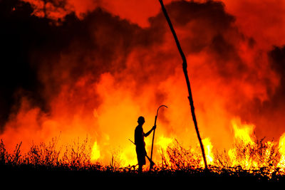 Rear view of man standing on field against sky during sunset