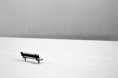 Snow covered bench on field