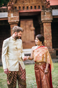 Couple holding hands while standing against building