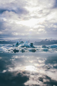 Snow covered landscape against cloudy sky