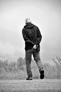 Rear view of man walking on land against sky