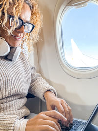 Midsection of woman using mobile phone while sitting at airport