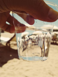 Close-up of hand on glass at beach