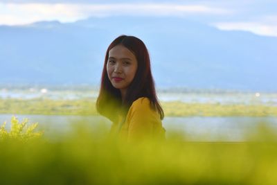 Portrait of smiling young woman against sky