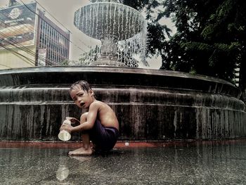 Portrait of boy sitting by fountain