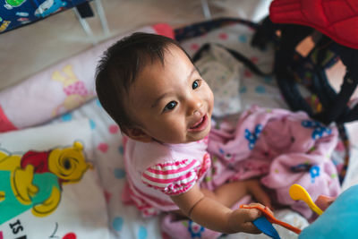 Baby girl sitting on bed at home