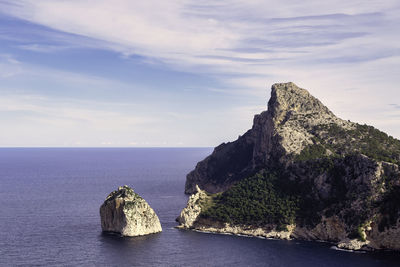 Rock formation by sea against sky