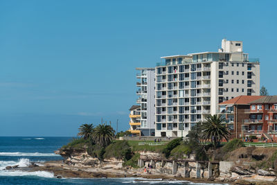 Building by sea against clear blue sky