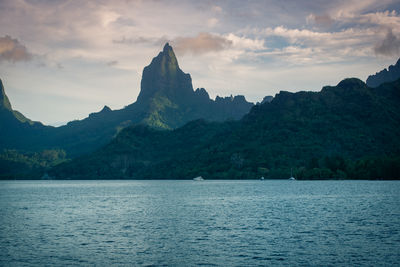 Scenic view of sea by mountains against sky