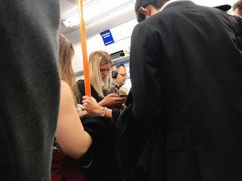 Midsection of couple holding while standing in bus