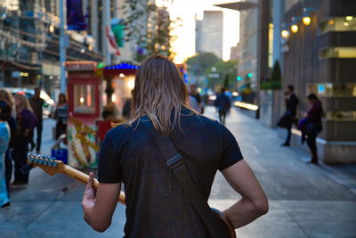 Rear view of woman standing on street in city