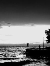 Silhouette man in sea against sky