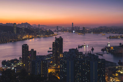 High angle view of illuminated buildings by river against sky