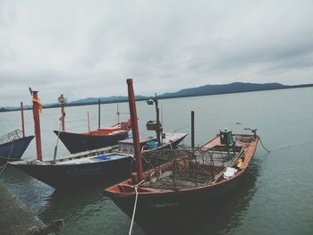 Fishing boats moored on sea against sky