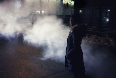 Side view of woman walking on street at night
