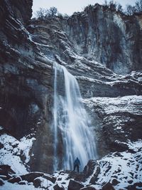 Scenic view of waterfall with man standing on rock