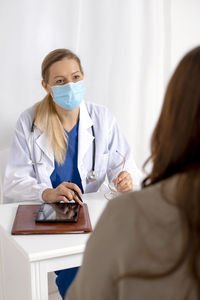 Young brunette woman having consultation at doctor office during coronavirus and flu outbreak. 