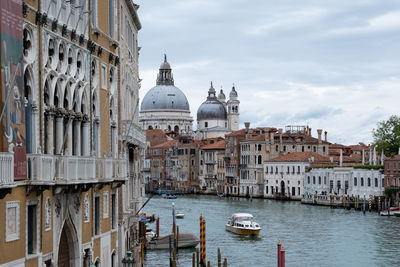 Boats in canal by buildings in venice against sky
