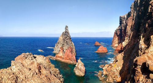 Panoramic view of rock formations in sea against sky