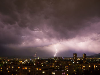 Lightning over illuminated buildings in city at night