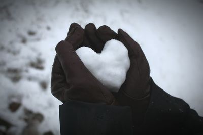 Midsection of woman holding snow covered hand during winter