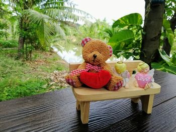 Stuffed toy on table against trees