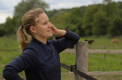 Young girl standing by fence on field