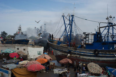 Boats moored at harbor against sky