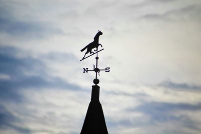 Low angle view of weather vane against sky