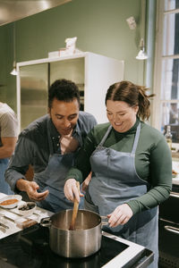 Male and female students preparing food during cooking class in kitchen