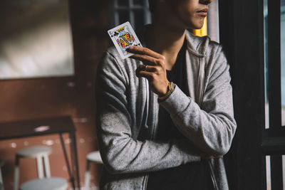 Midsection of man standing with king of clubs by door