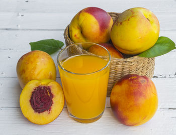 Delicious and juicy peach  with glass of juice on white wooden table