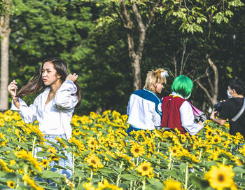 People standing on field by flowering plants