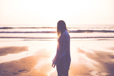 Woman looking at sea shore against sky