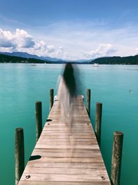 Wooden jetty on pier over lake against sky