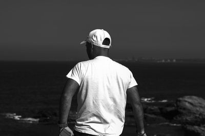 Rear view of man looking at sea against sky