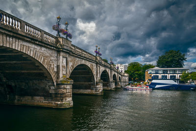 Bridge over river against cloudy sky