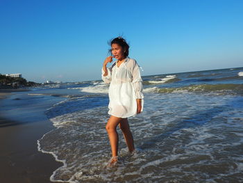 Woman standing on beach against clear sky