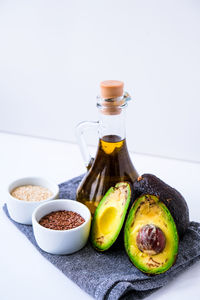 Olive oil in glass bottle with sesame and flax seeds. fresh ripe hass avocado. healthy eating. vegan