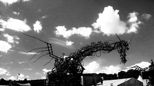 Low angle view of amusement park against cloudy sky