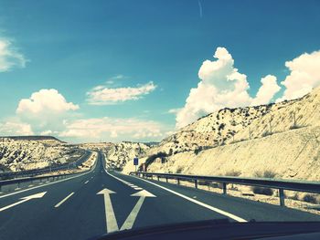 Diminishing perspective of road amidst mountains against sky seen through car windshield