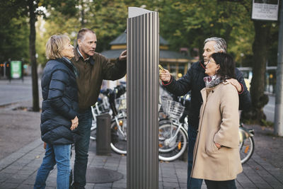 Two senior couples making payment at bike rental station