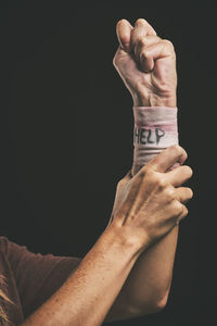 Cropped hand of man holding paper currency against black background