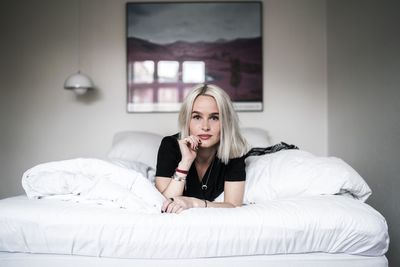 Portrait of young woman lying on bed at home