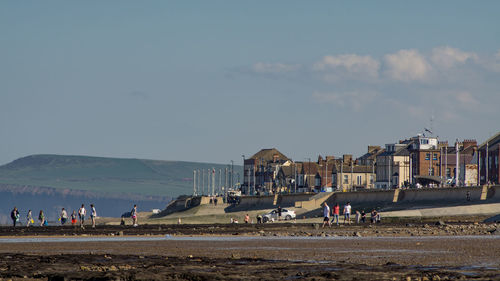 People on beach by buildings against sky