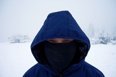 Portrait of man wearing hooded shirt against sky