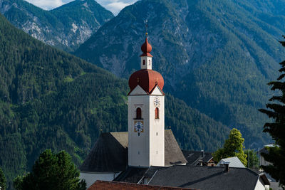 Tower amidst buildings and mountains against sky